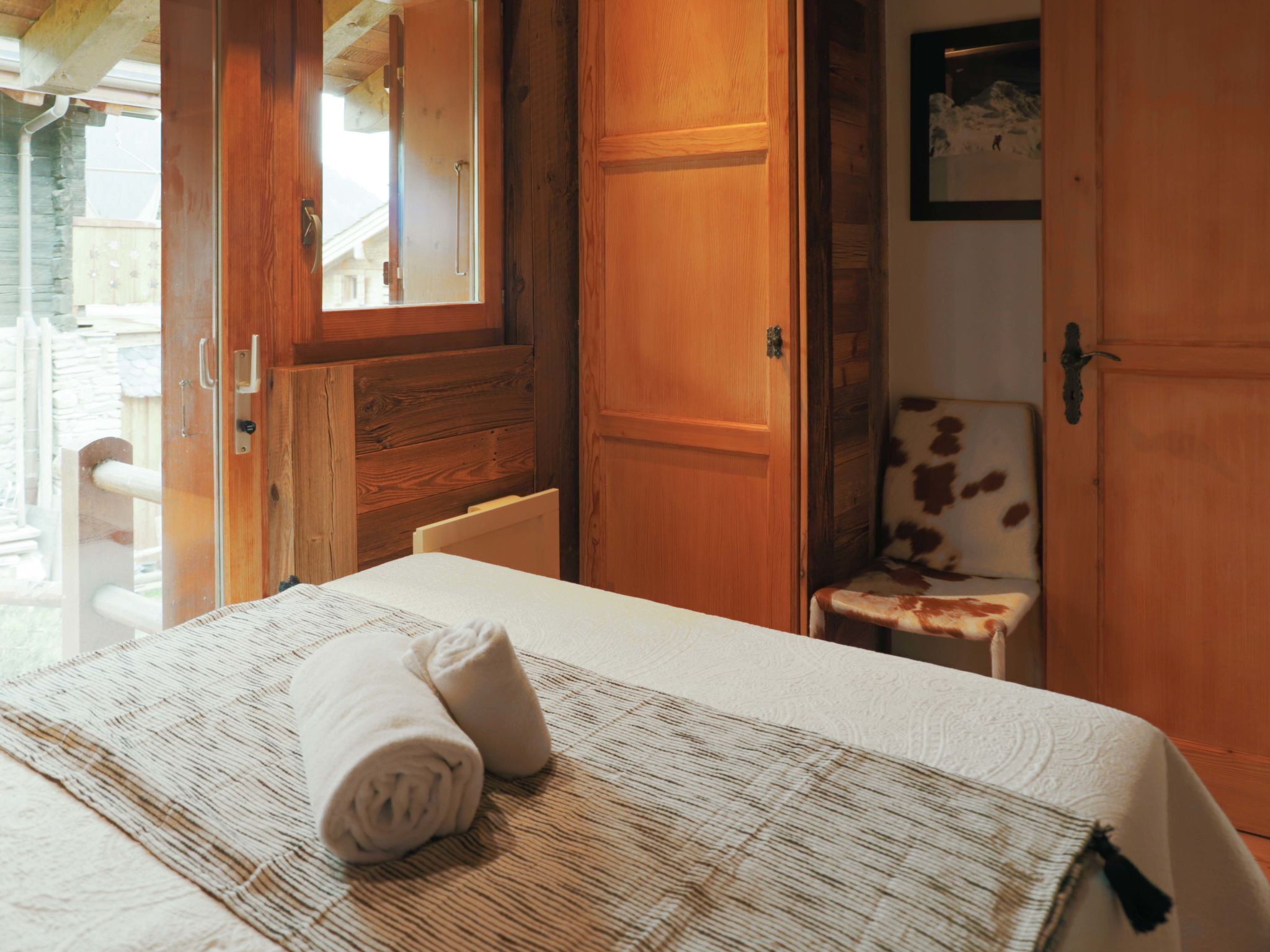 Ein Hotelzimmer mit einem Bett, einem Sessel und Holztüren.