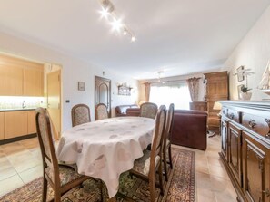 A dining area with a round table, floral chairs, a sofa, and a cabinet.