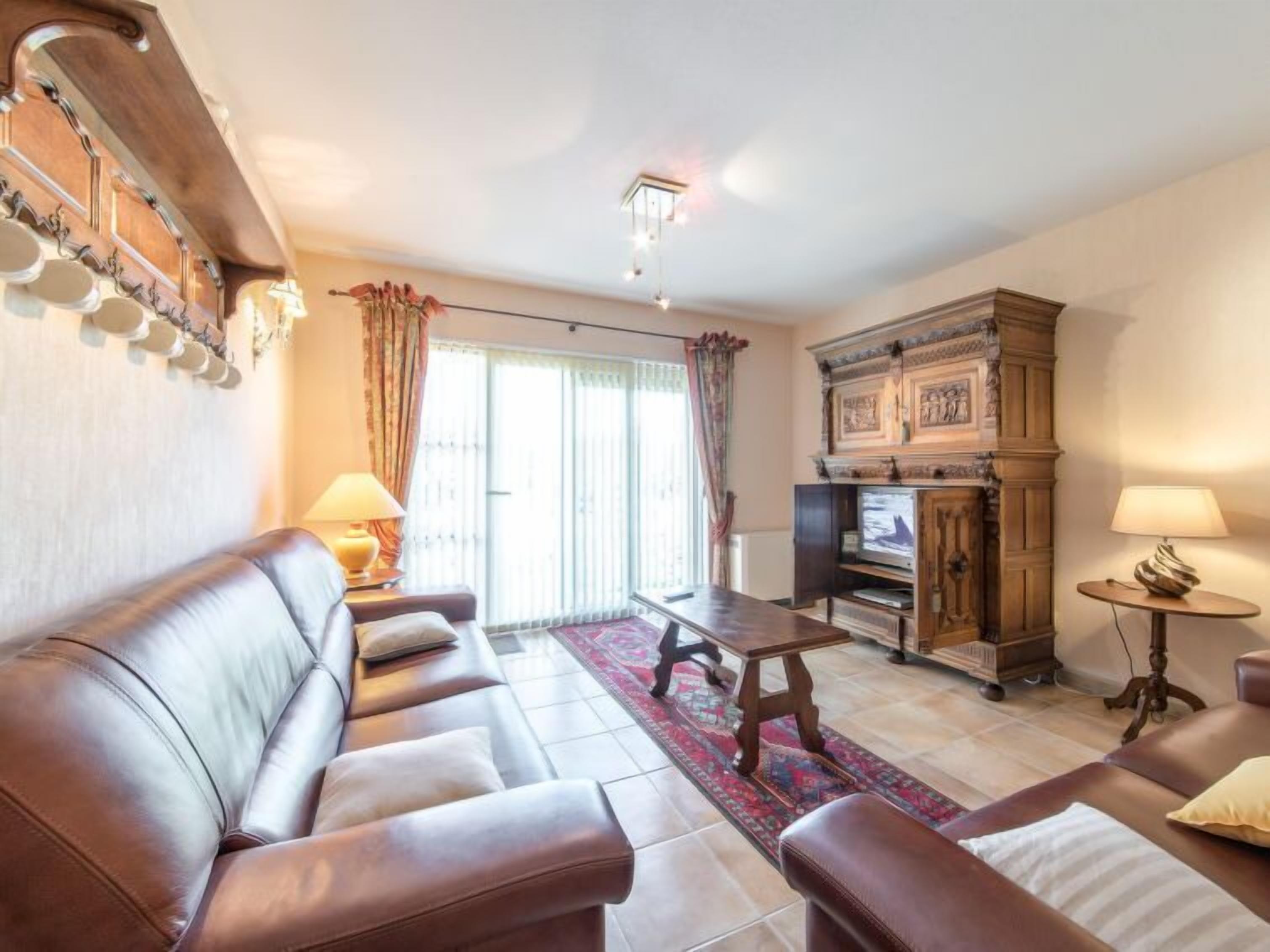 A living room with leather sofas, a coffee table, a TV, and a cabinet.