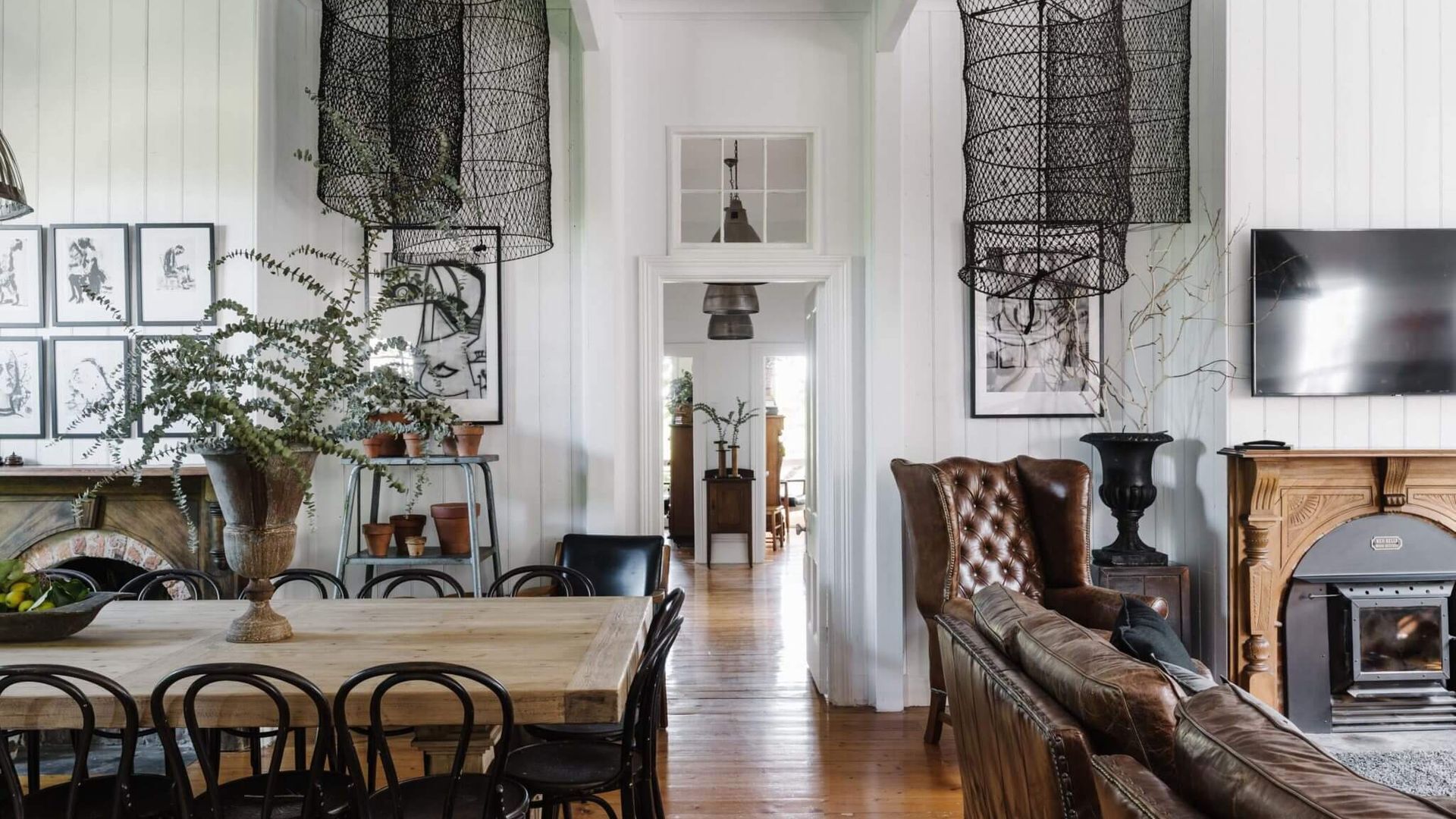 A dining area with a wooden table and chairs, a fireplace, and a television mounted on the wall.