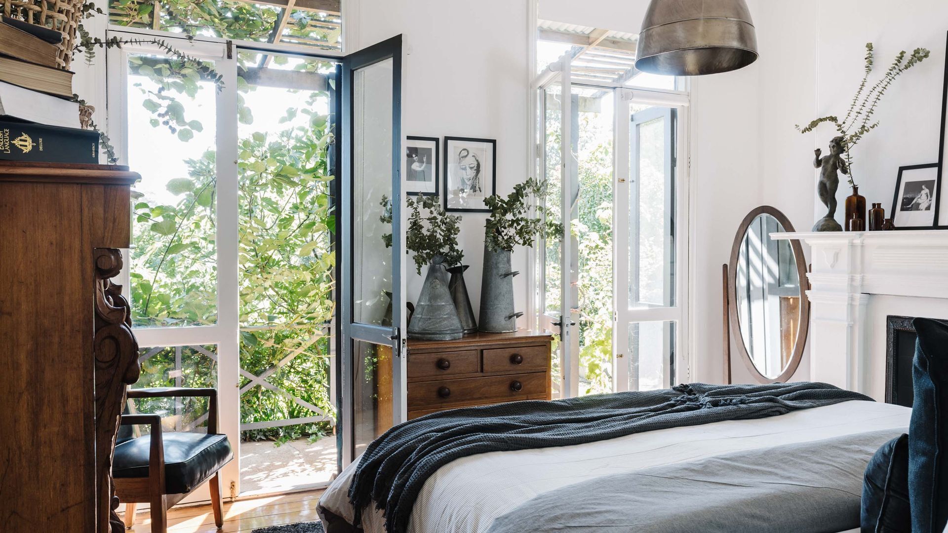 Ein Schlafzimmer mit Bett, Schminktisch und Blick auf Grünflächen.