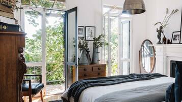 Ein Schlafzimmer mit Bett, Schminktisch und Blick auf Grünflächen.