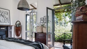 A bedroom with a bed, a dresser, a mirror, and a large window.