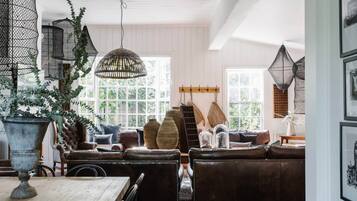 Ein gemütliches Wohnzimmer mit einer Ledersofa, einem Esstisch und hängenden Korbwannen.