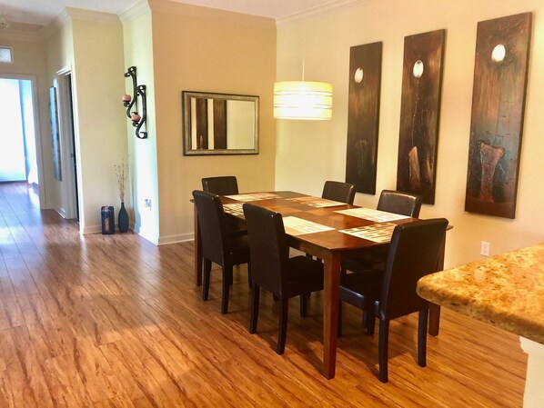 A dining area with a wooden table, black chairs, and a hanging light fixture.