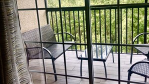 A balcony with wicker furniture and a view of trees. - Magical Tuscan Experience (Champions Gate)