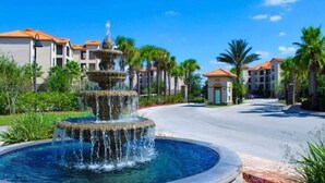 A multi-tiered fountain in a landscaped area with palm trees and buildings in the background. - Magical Tuscan Experience (Champions Gate)