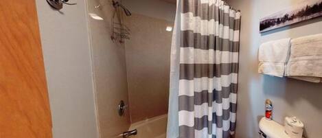 A bathroom with a shower, toilet, and towel rack.