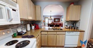 A modern kitchen with wooden cabinets, a built-in microwave, a stove, and a dishwasher.