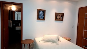 Ein Schlafzimmer mit einem Bett, einem kleinen runden Tisch und zwei gerahmten Bildern an der Wand.
