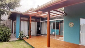 Ein modernes Haus mit einer Holzterrasse, großen Schiebegläsern und einer blauen Außenwand.