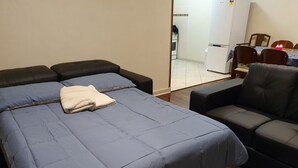 A bedroom with a bed, a chair, and a small table.