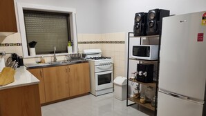 A kitchen with wooden cabinets, a gas stove, a microwave, and a refrigerator.