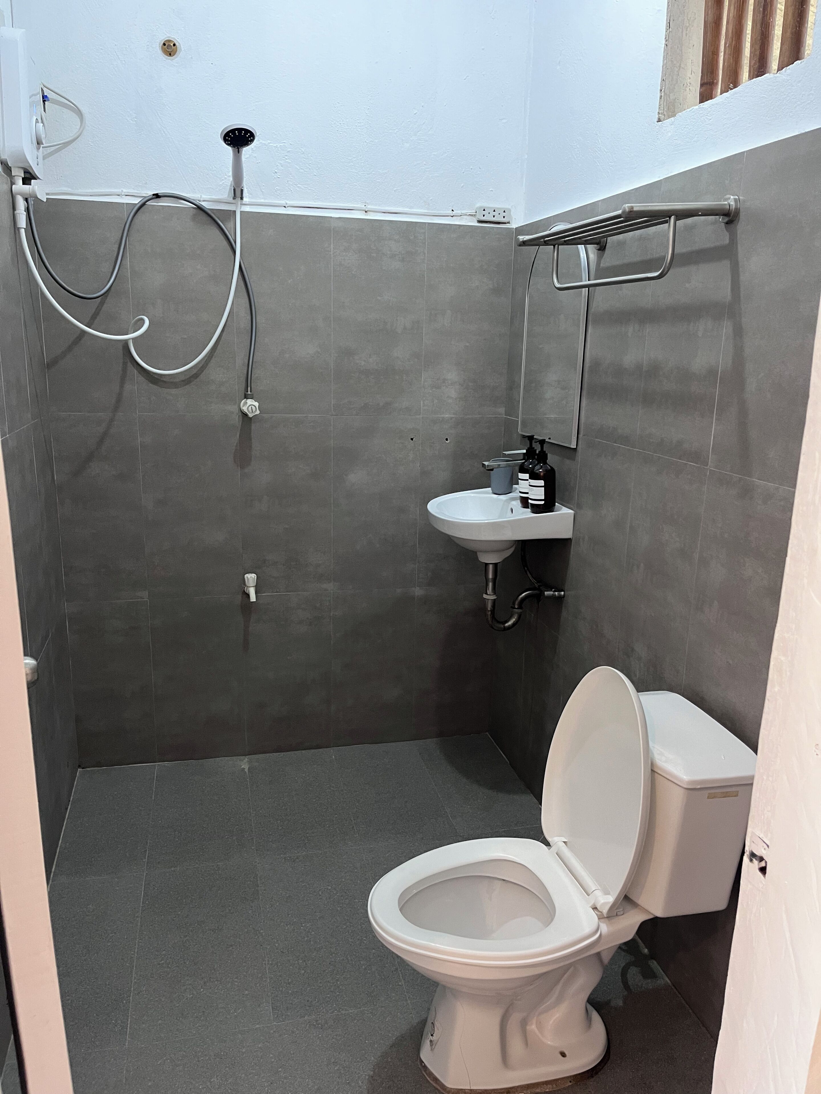 A compact bathroom with a white toilet, a small sink, and a shower area.