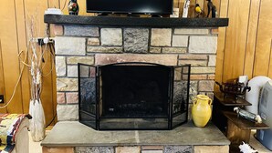 A stone fireplace with a TV above it, a small shelf with decorative items, and a vase on the mantel. - Come and enjoy the Breath taking  Vacation cabin at  Pocono , PA (pocono lake)