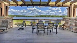 An outdoor deck with a table and chairs, overlooking a body of water and a distant shoreline. - Come and enjoy the Breath taking  Vacation cabin at  Pocono , PA (pocono lake)