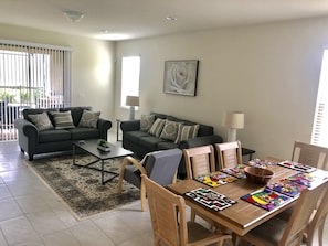 A living room with two sofas, a coffee table, a dining table with chairs, and a painting on the wall.