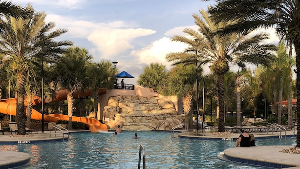 A swimming pool with a water slide, palm trees, and a rock formation. - Solterra Resort - is a beautiful paradise located in Davenport, near to Orlando (Davenport)