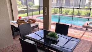 A patio area with a glass table, wicker chairs, and a view of a swimming pool. - Solterra Resort - is a beautiful paradise located in Davenport, near to Orlando (Davenport)