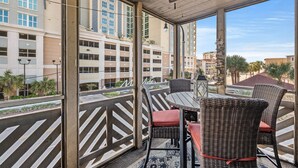 A balcony with wicker furniture and a view of a parking garage. - Waipani E14-2BR -Beach Across The Street-Pool (North Myrtle Beach)