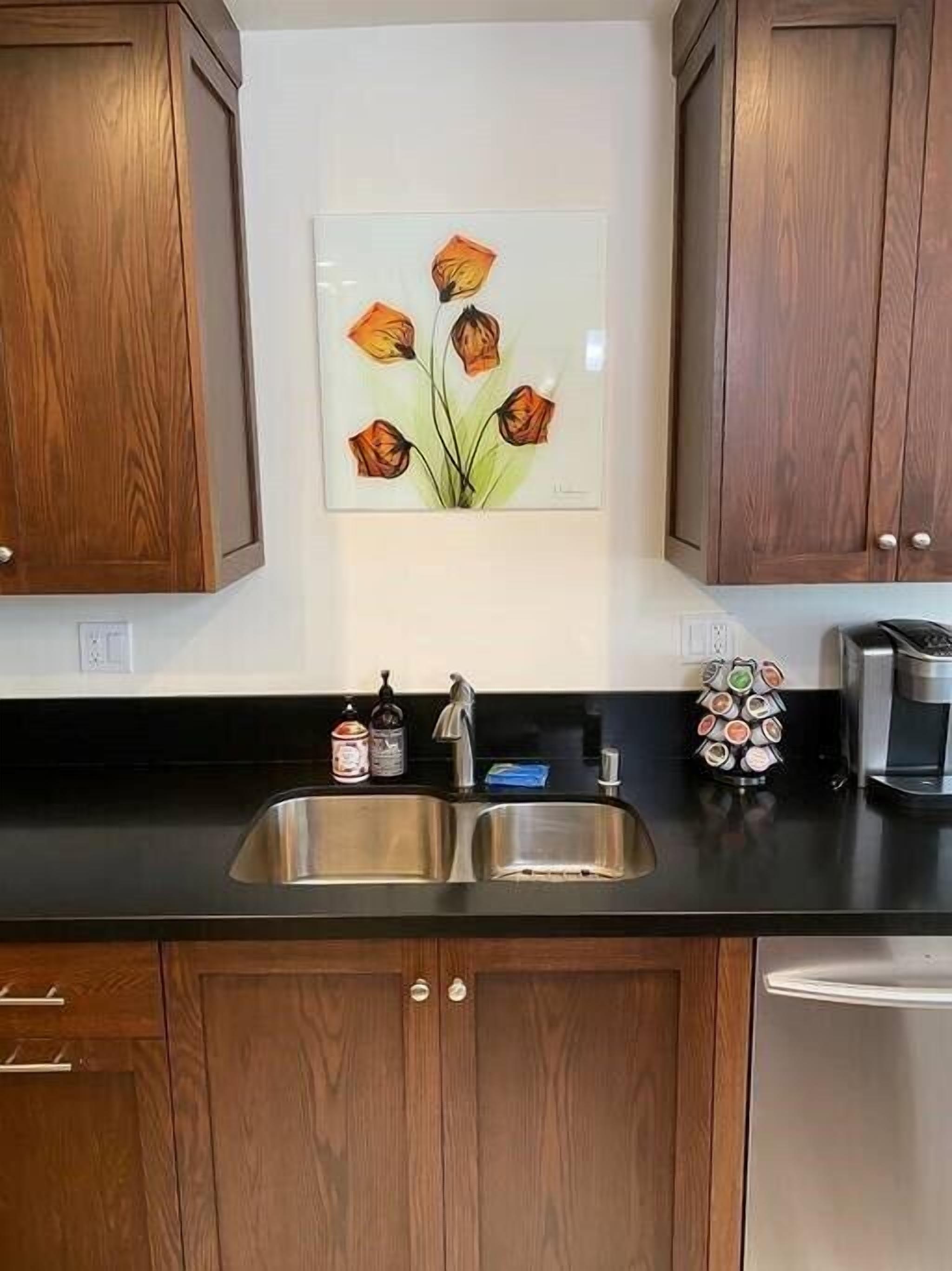 A kitchen with wooden cabinets, a stainless steel sink, and a coffee maker.