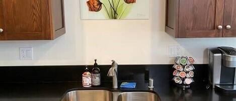 A kitchen with wooden cabinets, a stainless steel sink, and a coffee maker.