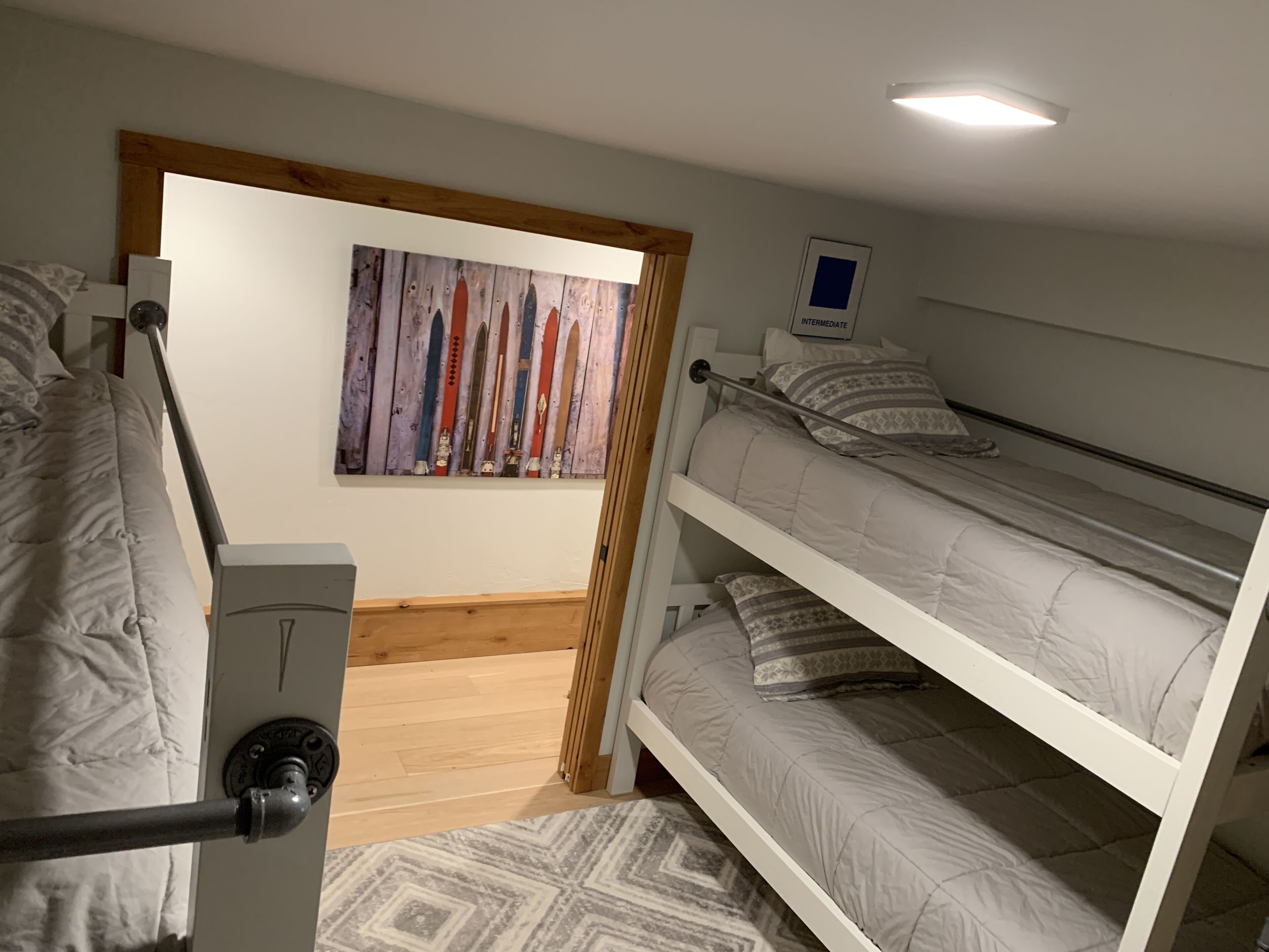 A bunk bed room with a wooden door, a painting on the wall, and a small window labeled "INTERMEDIATE".