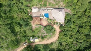Eine Vogelperspektive zeigt ein Haus mit Swimmingpool, umgeben von dichtem Wald.