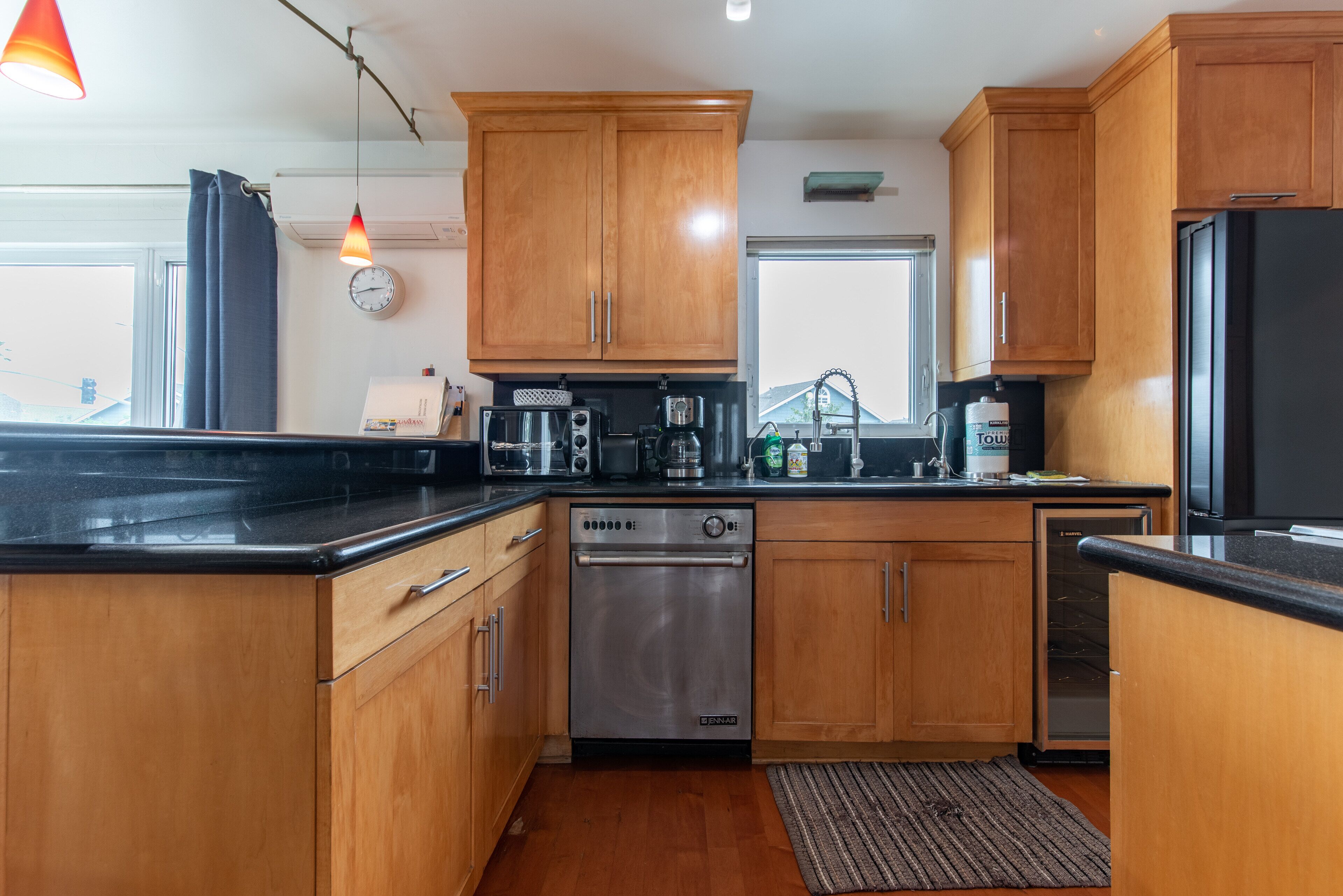 A modern kitchen with wooden cabinets, stainless steel appliances, and a black countertop.