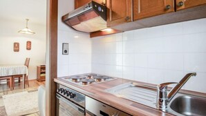 Eine moderne Küche mit Holzschränken, einem Edelstahlherd, einem Einbauofen und einem Spülbecken.