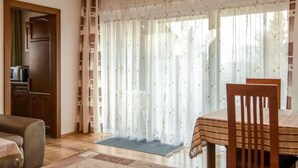 Ein gemütliches Wohnzimmer mit einer Couch, einem Esstisch mit Stühlen, einer Holzkabine und einer Küchenzeile mit einer Mikrowelle.