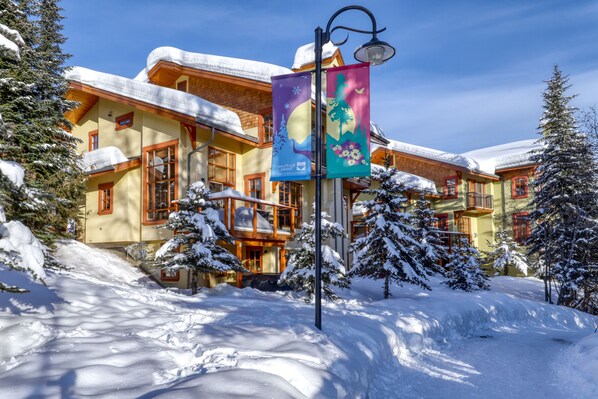 A snow-covered building with a balcony and a street lamp.
