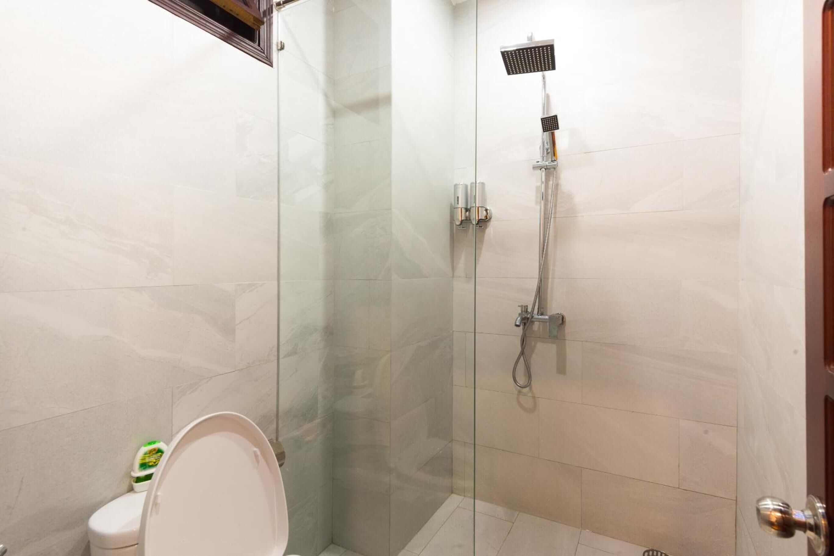 A modern bathroom with a glass-enclosed shower, a toilet, and a sink.