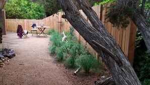 A garden area with a wooden fence, a table, and chairs. - Treescape, Seascape Getaway (Ocean Grove)