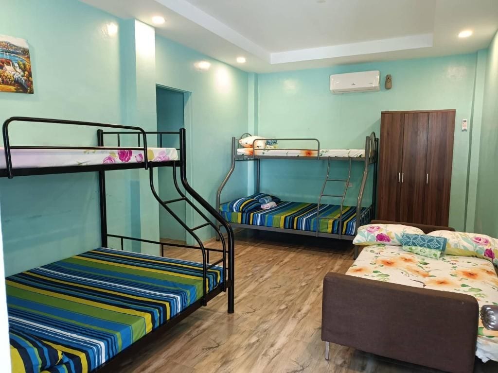 A dormitory room with bunk beds, a wardrobe, and a single bed.