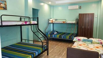 A dormitory room with bunk beds, a wardrobe, and a single bed.
