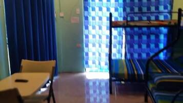A room with a bunk bed, a table with chairs, and a window with curtains.