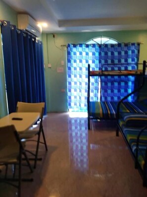 A room with a bunk bed, a table with chairs, and a window with curtains. - Azulea Lodging House Oslob (Oslob)