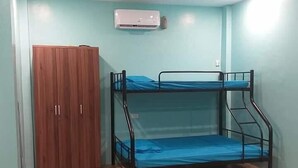A room with a bunk bed, a wooden wardrobe, and a sofa.