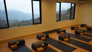 Ein Yogastudio mit für die Praxis bereitgestellten Matten und Blöcken, große Fenster mit Blick auf Berge.