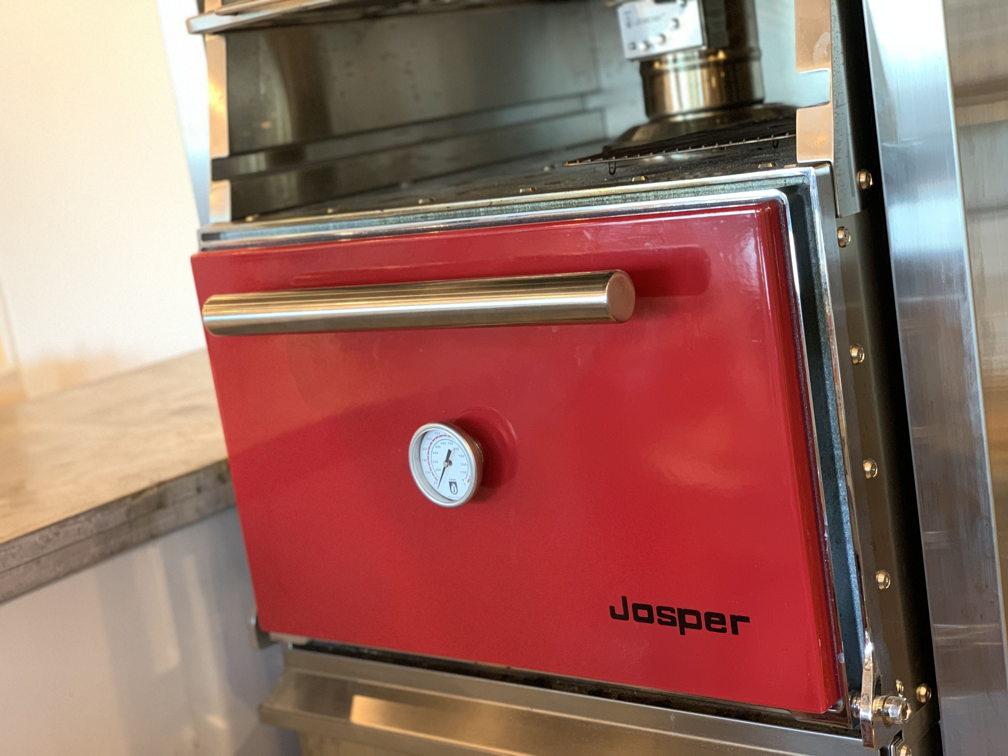 A red kitchen appliance with a pressure gauge and the brand name 'Josper' on it.