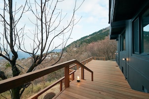 Una terraza de madera con barandilla, con vistas a un paisaje montañoso.