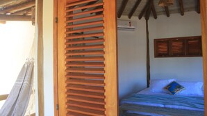 A bedroom with a bed, wooden shutters, a hammock, and a ceiling fan. - Pousada Vila Cacau (Uruçuca)