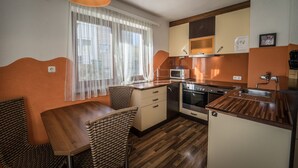 A compact kitchen with a dining area, featuring a microwave, stove, and wooden cabinets. - Casa Melissa (Schönberg im Stubaital)