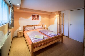 A bedroom with a wooden bed, two bedside tables, a radiator, and a door.