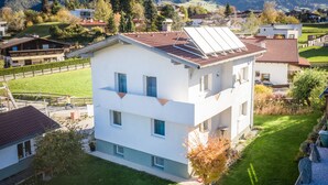 A modern two-story house with a sloped roof, a small front yard, and a visible swimming pool in the background. - Casa Melissa (Schönberg im Stubaital)