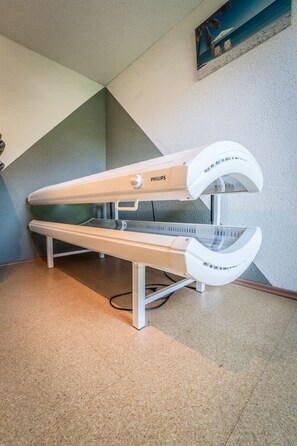 A Philips MRI machine in a clinical setting with a tiled floor and a painting of a beach scene on the wall.