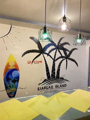 A room with a mural of palm trees and a surfboard, a logo for 'DALTANS HOMESTAY', and a sign reading 'SIARGAO ISLAND PHILIPPINES'. - Daltans Home Stay (General Luna)