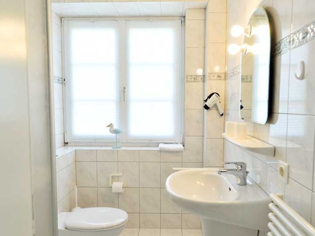 A bathroom with a toilet, bidet, sink, and a window.