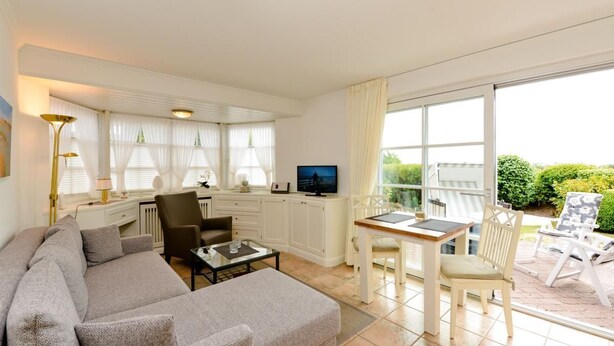 A modern living room with a sofa, coffee table, and dining area. - Apartment Tietje, Germany (Sylt)